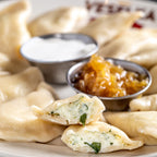 Arugula and goat cheese pierogi cut open, boiled on a plate 