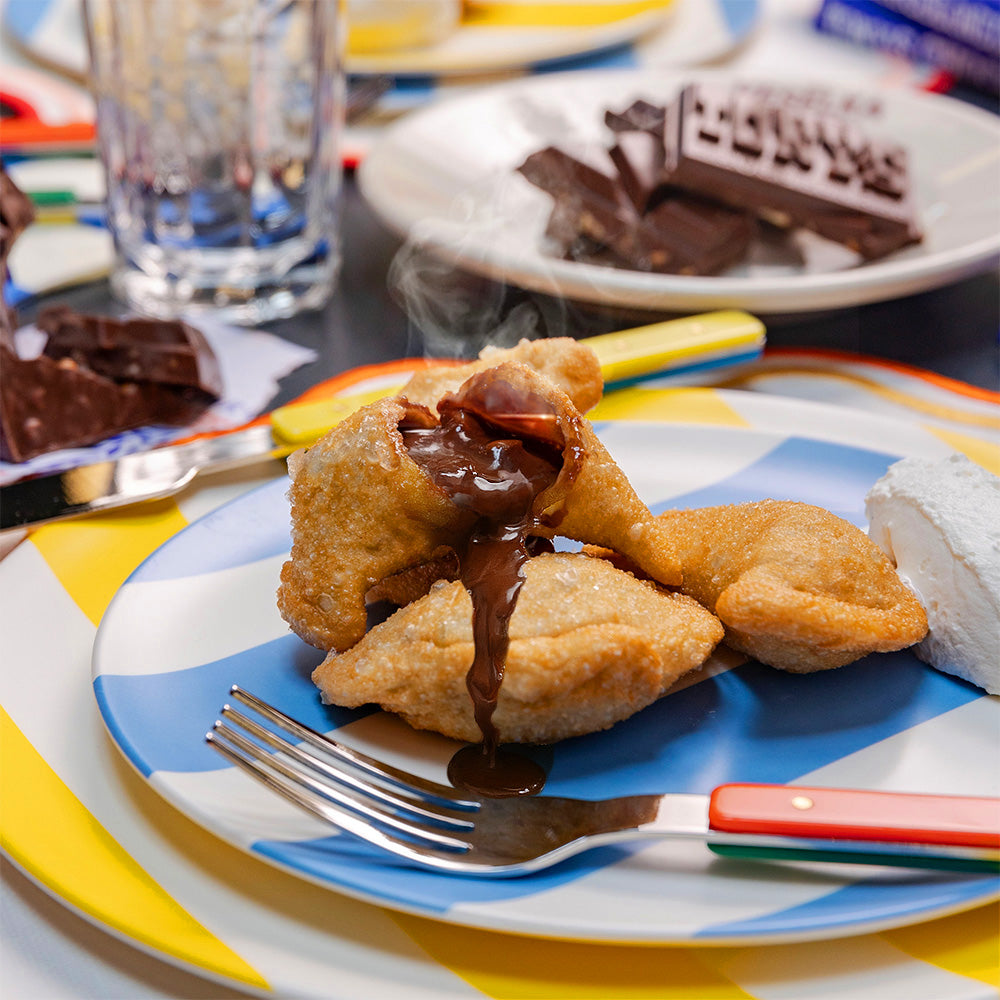 Chocolate gooey pierogi, fried on striped colorful plate. Tony